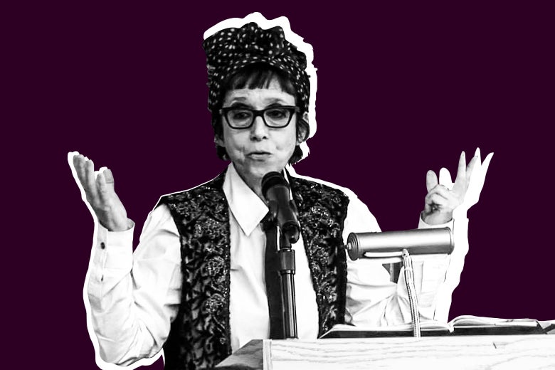 Avital Ronell shrugs, while speaking from a podium.